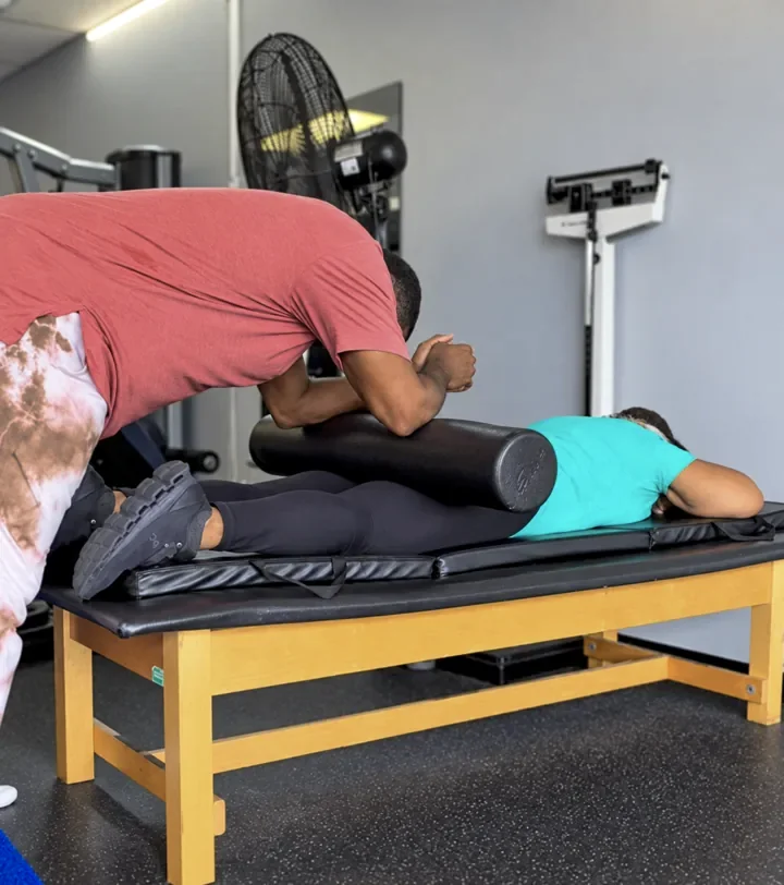 Coach Cal assisting a client with foam-roller work at Infinite Fitness